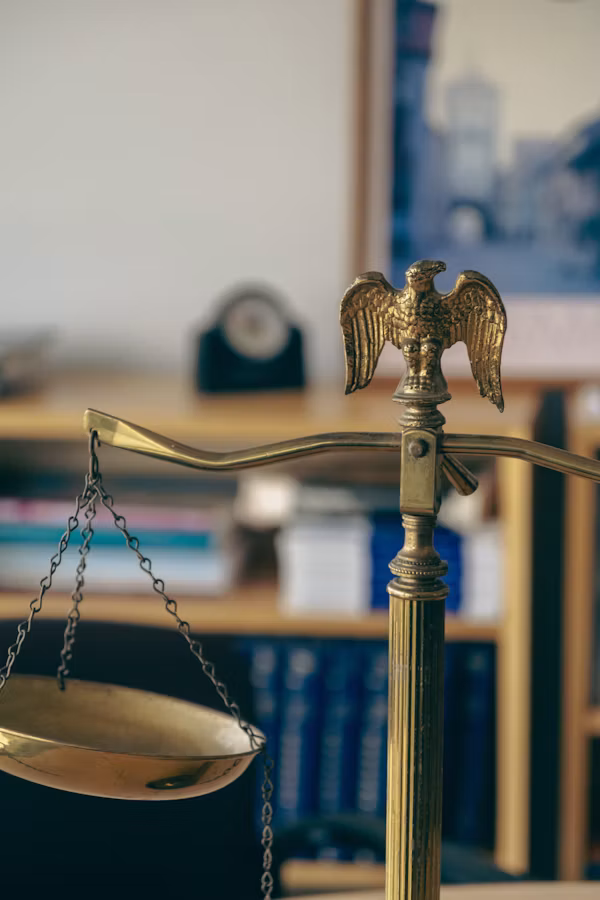 Brass scales of justice on a desk with law books in the background